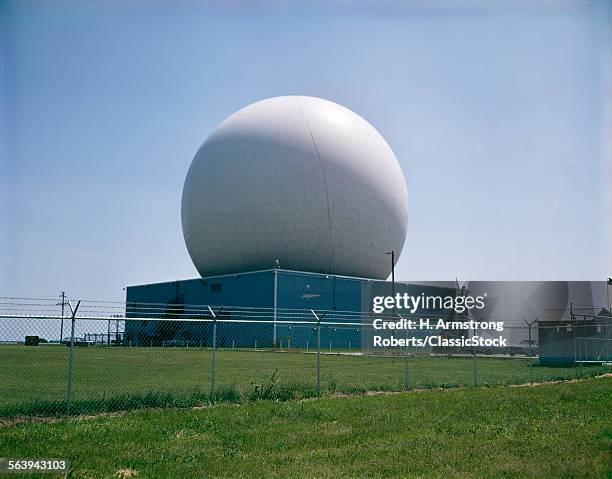 1960S EXTERIOR RADAR DOME SATELLITE COMMUNICATION SURROUNDED BY CHAIN LINK FENCE