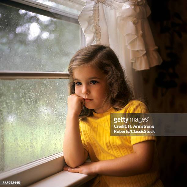 1970s YOUNG GIRL SAD PENSIVE THINKING RAIN ON WINDOW PANE
