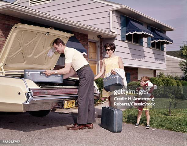 1960s 1970s FAMILY COUPLE WITH LITTLE DAUGHTER HOLDING BIG TEDDY BEAR LOADING LUGGAGE INTO AUTOMOBILE TRUNK FOR VACATION