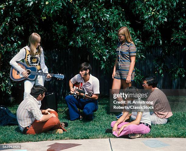 1960s 1970s GROUP OF 6 TEENS BOYS GIRLS IN BACKYARD SUMMER 1 BOY 1 GIRL PLAYING GUITAR SIDEBURNS FASHION