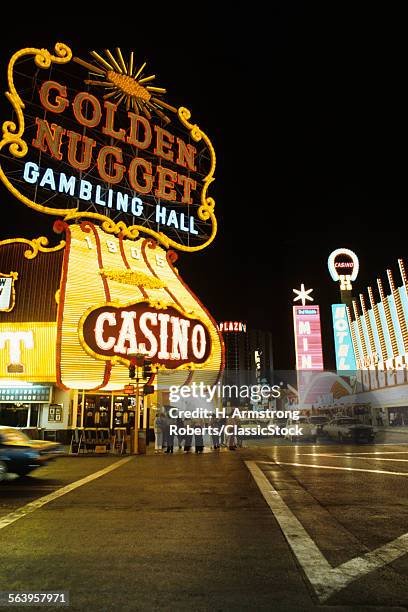 1970s FREMONT STREET DOWNTOWN LAS VEGAS NEVADA AT NIGHT WITH NEON OF GOLDEN NUGGET HORSESHOE AND MINT CASINOS