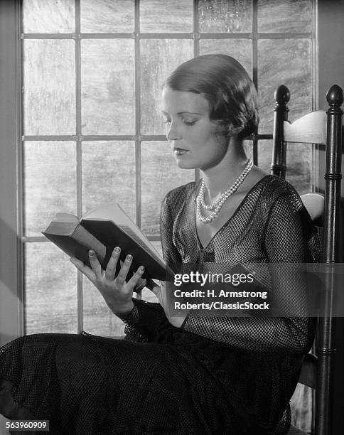 1920s 1930s ELEGANT WOMAN WEARING PEARLS SITTING BY WINDOW READING BOOK