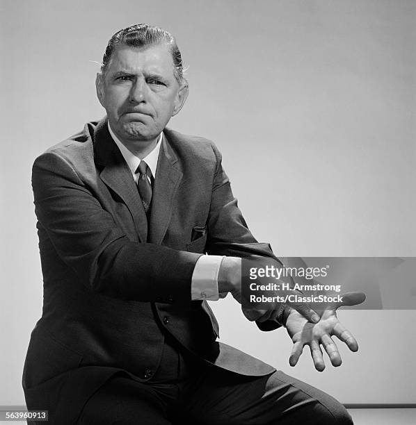 1960s ANGRY MAN POINTING TO PALM OF HIS HAND
