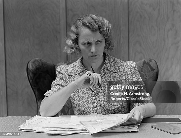 1930s SERIOUS WORRIED WOMAN AT DESK GOING OVER PAPERS BILLS LOOKING OFF TO SIDE