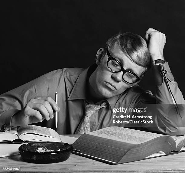 1970s YOUNG MAN STUDYING READING BOOKS LEANING ON ARM