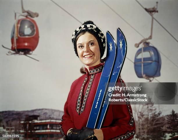 1950s SMILING BRUNETTE WOMAN IN RED TOP HOLDING BLUE SKIS BY SKI LIFT