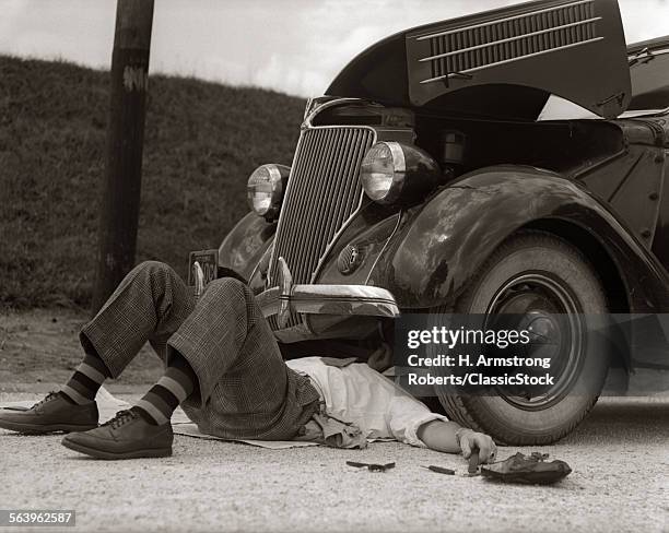 1930s MAN ON BACK WEARING STRIPED SOCKS FIXING CAR