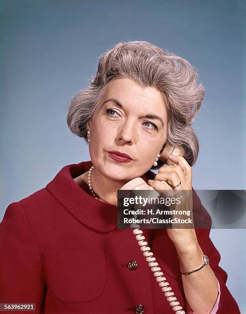 1960s SENIOR MIDDLE AGED WOMAN RED BLOUSE SERIOUS EXPRESSION TALKING ON TELEPHONE