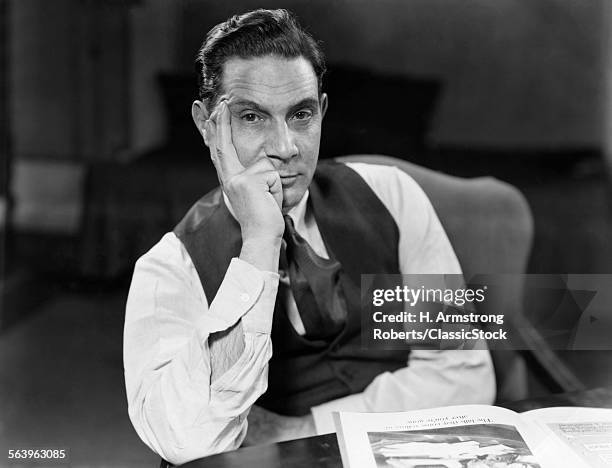 1930s 1940s MAN SEATED ELBOWS ON TABLE FACE LEANING ON HAND SERIOUS EXPRESSION WEARING SHIRT TIE VEST LOOKING AT CAMERA