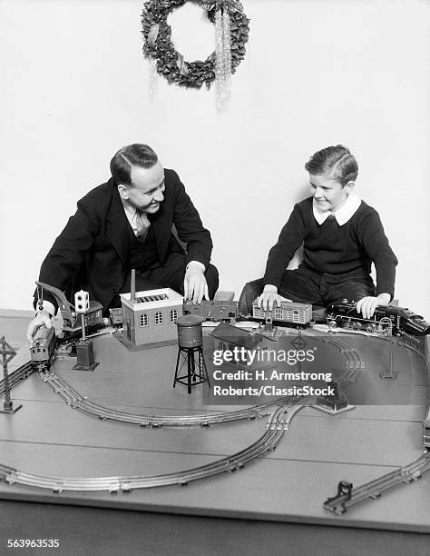 1930s FATHER AND SON PLAYING WITH CHRISTMAS TOY TRAIN SET