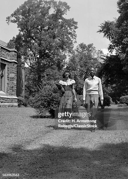 1940s 1950s AFRICAN AMERICAN COLLEGE COUPLE WALKING ON CAMPUS CARRYING BOOKS