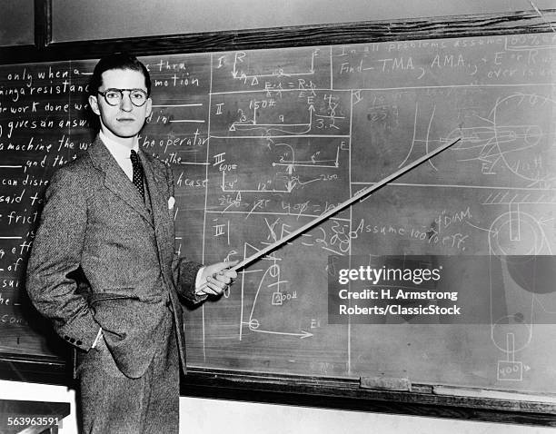 1930s 1940s MAN TEACHER PROFESSOR POINTING POINTER AT BLACKBOARD LOOKING AT CAMERA