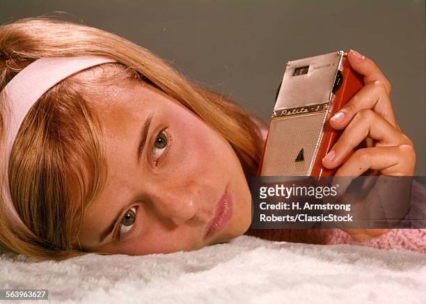 1960s TEEN TEENAGE GIRL HOLDING RED & SILVER SMALL TRANSISTOR RADIO TO HER EAR LISTENING RADIOS