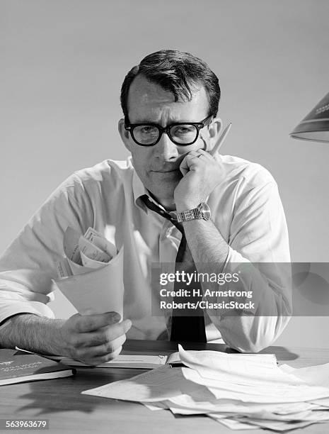 1960s MAN WITH PILE OF BILLS AND WORRIED EXPRESSION