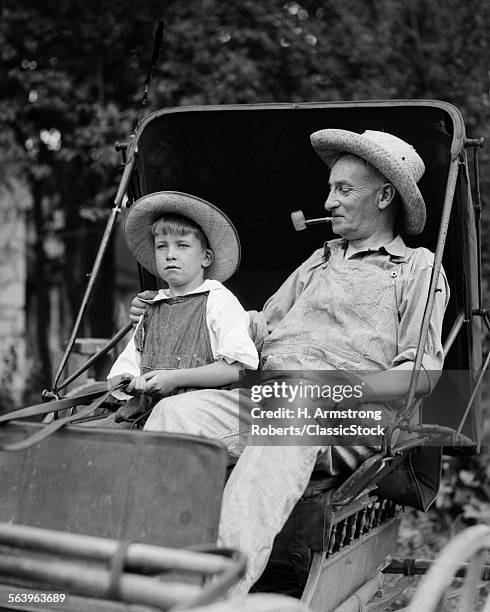 1930s FARM BOY & GRANDFATHER IN OVERALLS & STRAW HATS SITTING IN SMALL BUGGY