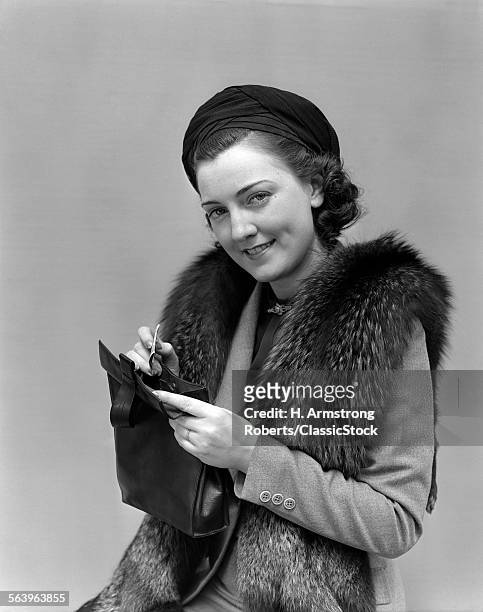 1930s 1940s WOMAN DRESSED UP WITH FUR JACKET HOLDING PURSE AND MONEY LOOKING AT CAMERA
