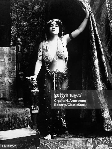 1900s 1910s VAMP WEARING A PEARL AND RUBY JEWELED HALTER AND HAREM PANTS STANDING SMOKING A CIGARETTE