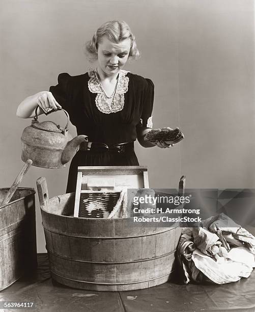 1940s DISPLEASED HOUSEWIFE POURING WATER FROM KETTLE INTO BUCKET WITH WASHBOARD & TOWEL