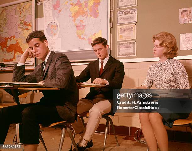 1960s 3 COLLEGE HIGH SCHOOL STUDENT STUDENTS SITTING DESK CHAIRS READING STUDY STUDYING CLASSROOM STUDY