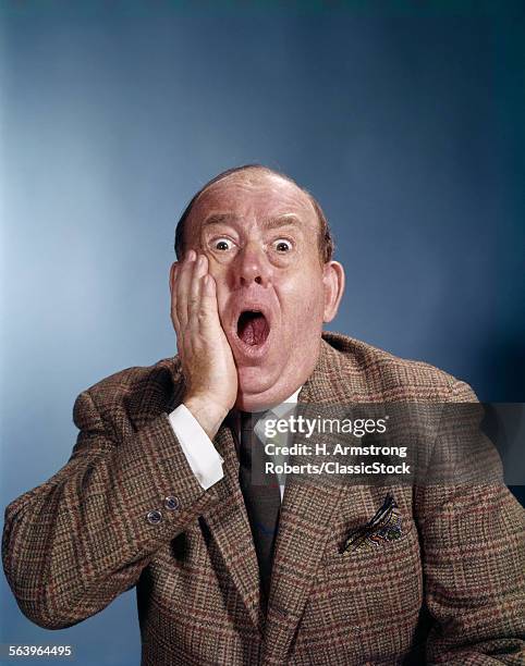 1960s BALDING BUSINESSMAN HOLDING HAND UP TO FACE SHOCKED EXPRESSION EYES BULGING MOUTH OPEN