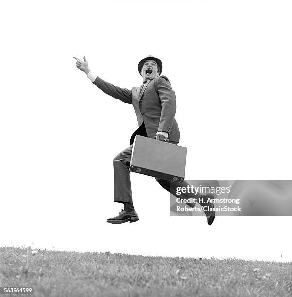 1960s BUSINESSMAN CARRYING A BRIEFCASE RUNNING YELLING AND JUMPING IN THE AIR OUTDOOR POINTING FINGER FORWARD