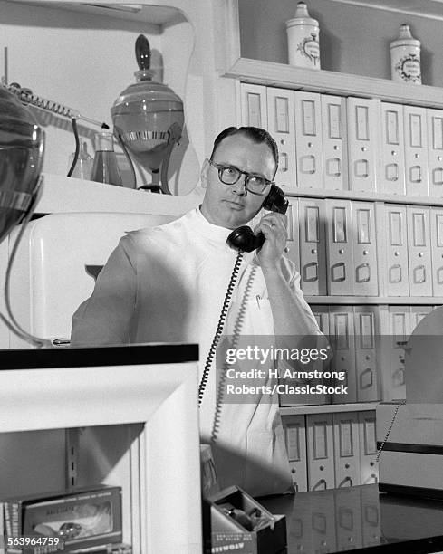 1950s MAN PHARMACIST BEHIND COUNTER ON PHONE