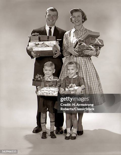 1960s FAMILY PORTRAIT OF FOUR MOTHER FATHER BOY GIRL CARRYING CHRISTMAS GIFTS WRAPPED PRESENTS