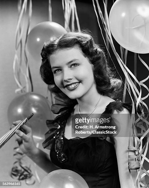 1940s 1950s SMILING WOMAN BLACK PARTY DRESS PEARLS HOLDING NEW YEAR PARTY NOISE MAKER STREAMERS BALLOONS BACKGROUND