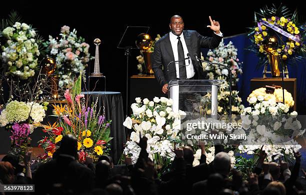 Former player Magic Johnson holds an "L" in honor of the Lakers team during a memorial service for owner Jerry Buss at the Nokia Theatre Thursday.