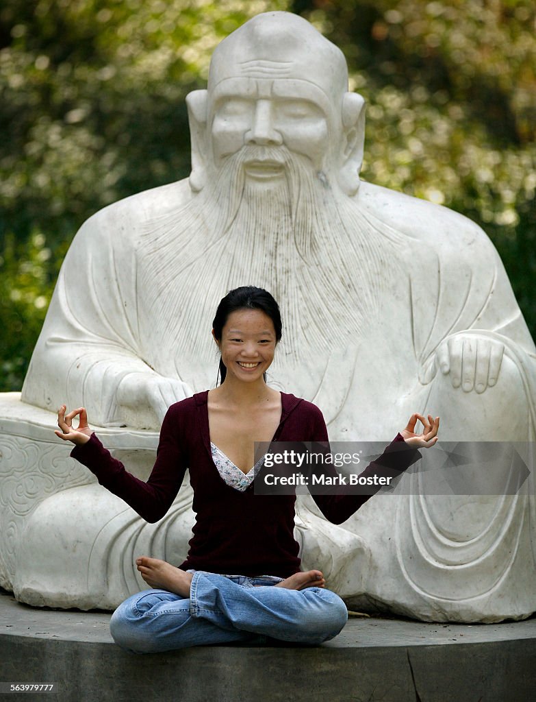 Joy Kuo,18, from Riverside poses while a friend takes her picture on the statue of "The Old Master"
