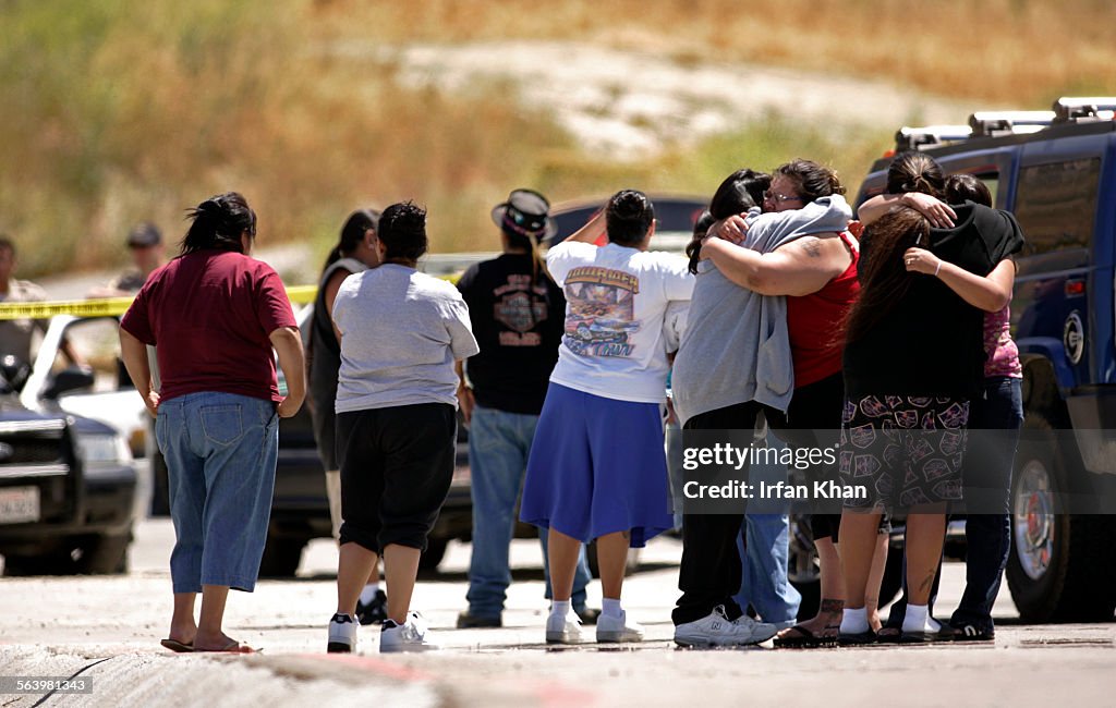 Grieving family members comfort each other at the road leading to crime scene where two unknown sus