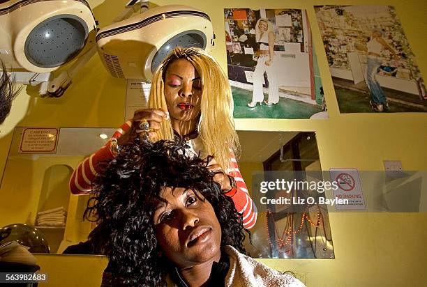 Sandra Dunn, of Nigeria, fixes a client's weave, as the other stylist picks up hair Dunn's salon in Brixton Market called "Looking Good Salon,"...
