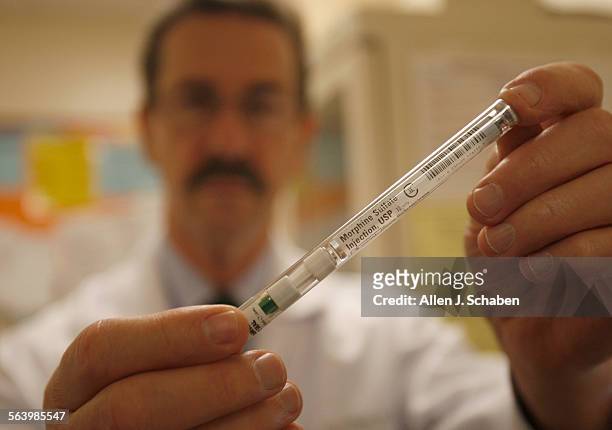 Dr. Brian Johnston, Chairman of the Dept. Of Emergency Medicine at White Memorial Hospital, holds a syringe of morphine sulfate, dispensed from an...