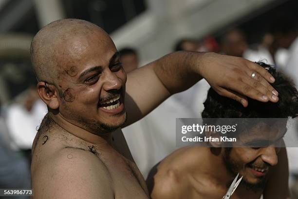 Mina. December 19, 2007.   After his head shaven Ramadan Al Mutwali Al Zuheri shares a light moment while clipping hair of his friend Emad Ali as a...