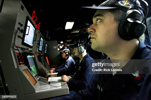 Randy Loewen, a sensor operator in the sonar room of the destroyer USS Momsen, inspects the monitors for signs of a submarine or marine mammals...