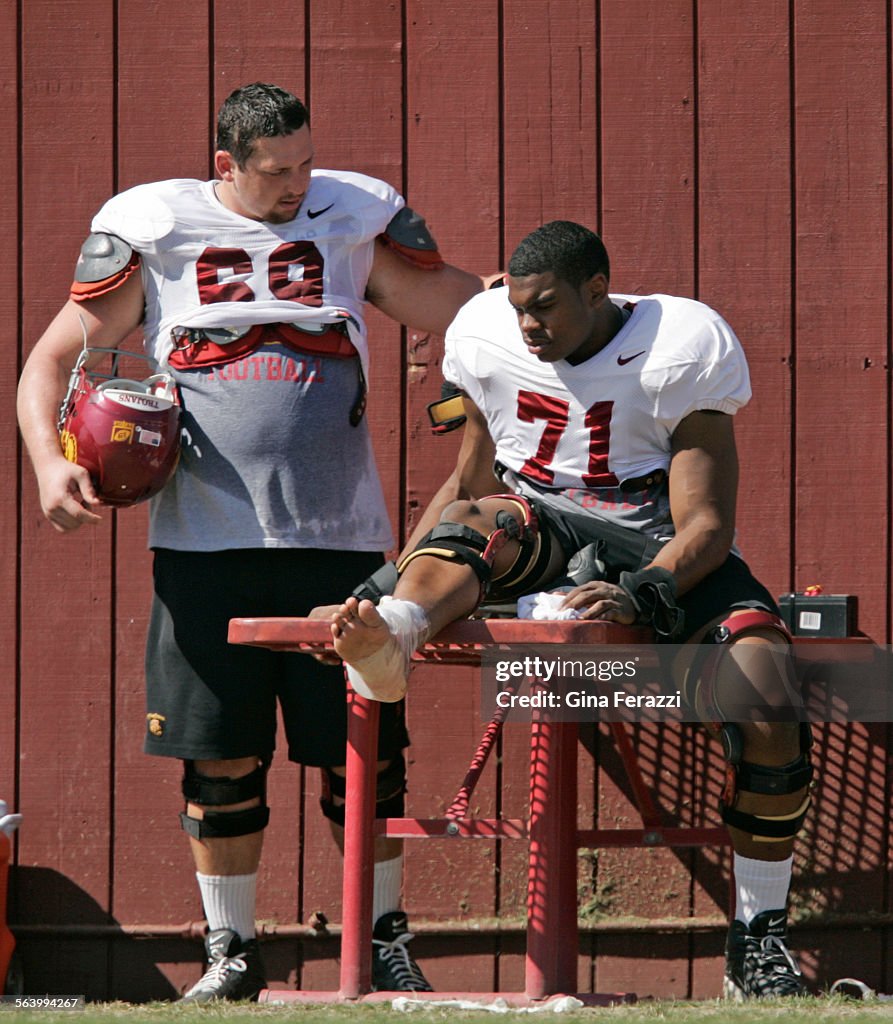 USC center Matt Spanos,left, checks on teammate offensive tackle Charles Brown, who's icing his ank