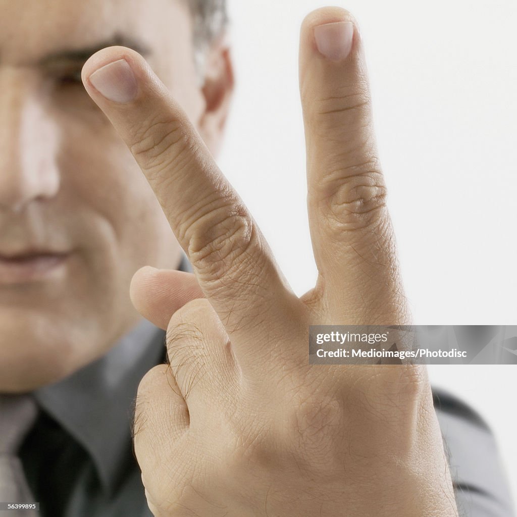 Mid Adult man holding two fingers out in peace sign