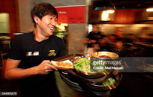 Phil Heo, a waiter at the Korean BBQ restaruant, Kang Ho Dong Baekjong, located in Chapman Plaza in the Koreatown section of Los Angeles, makes his...