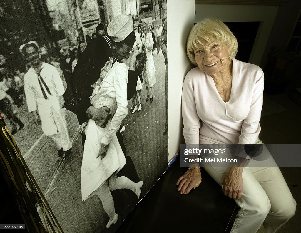 Edith Shain sits next to an enlarged photograph of her being kissed by a sailor in Times Square on