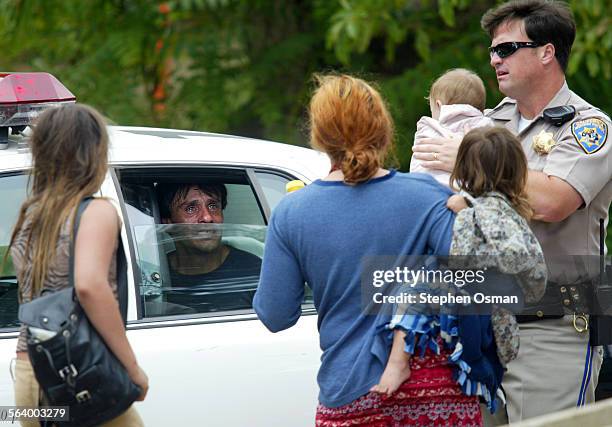 The father who was arrested after the pursuit talks with his family from the backseat of a LAPD patrol car. CHP officer John Valenti holds the infant...