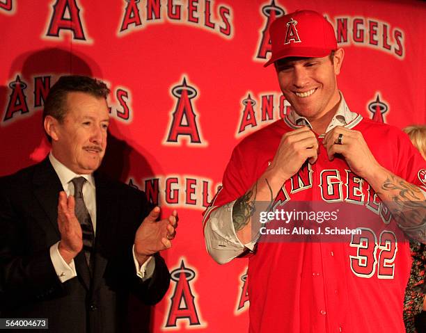 Angels owner Arte Moreno, left, cheers on his newest signing, outfielder Josh Hamilton, as he puts on his Angels jersey and hat during a press...