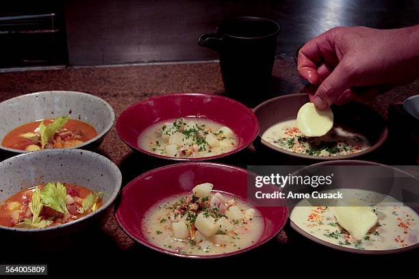 Chef Michael Cimarusti places a pad of butter on the New England creamy Clam Chowder, right, New England Calm Chowder clear, center and Manhattan...