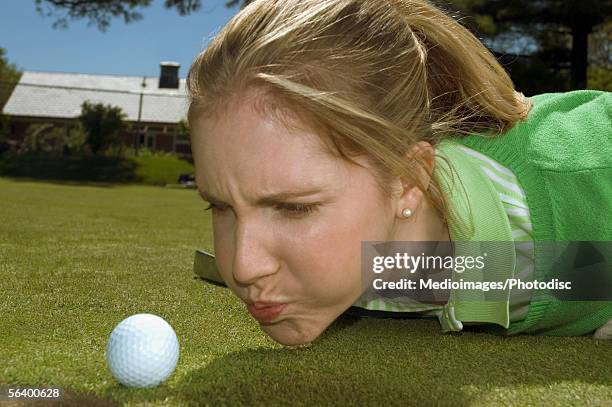 frustrated woman blowing on golf ball, close-up - golf cheating imagens e fotografias de stock