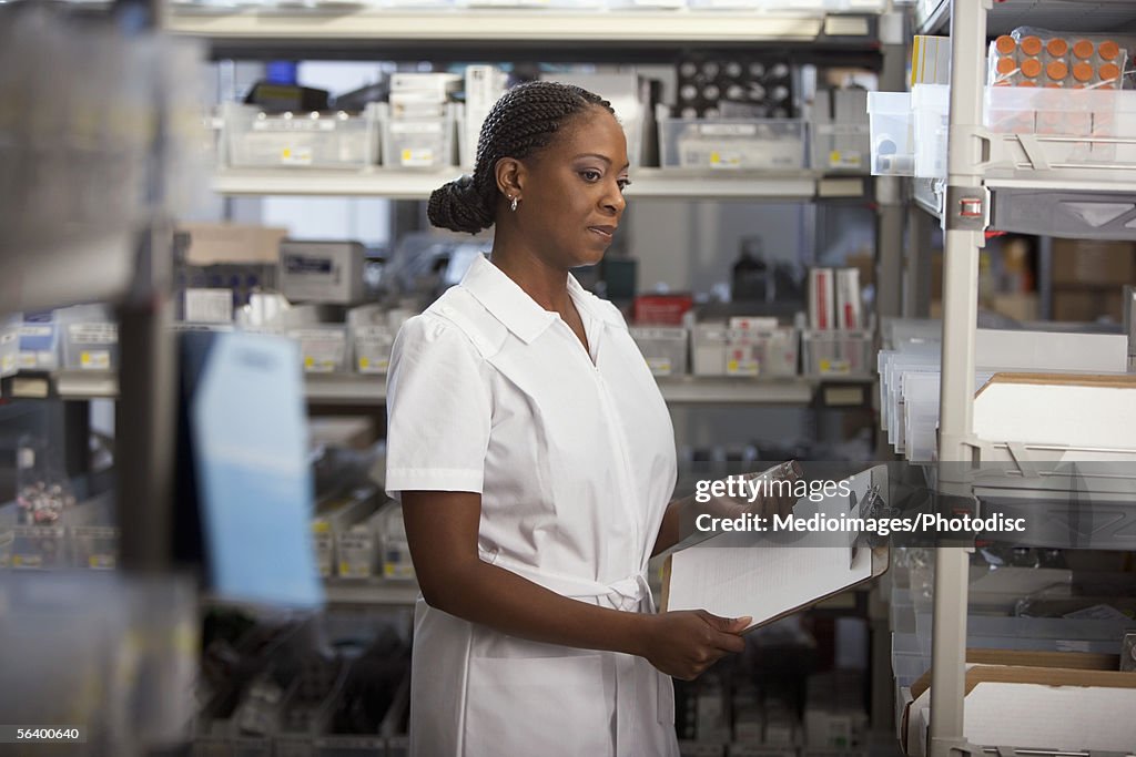 Healthcare worker looking down at bottle in hospital supply room