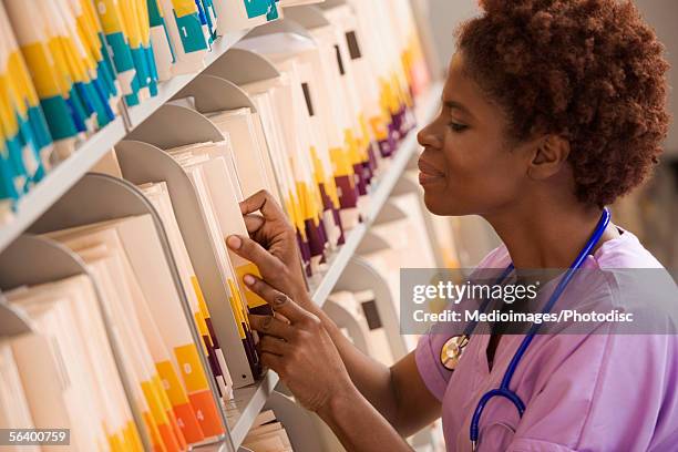 doctor getting file in medical records room - archivieren stock-fotos und bilder