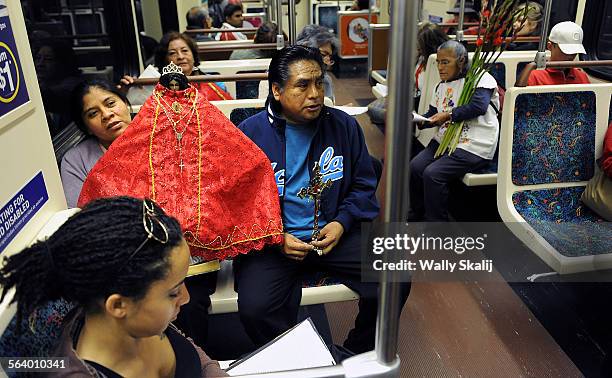 Matilde Cruz and her husband Oscar carry the Virgin of Juquila during a procession as Arlyn Reid reads a book on the metro from their home to the La...