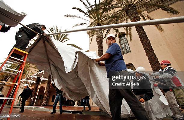 Workmen from Classic Party Rentals assemble tents in anticipation of rain along the red carpet arrivals area in front of the Shrine Auditorium...