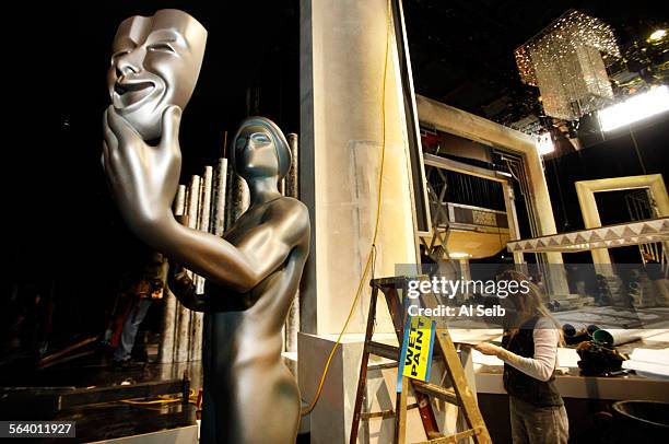 Dena D'Angelo, right, head scenic artist works to detail the stage Thursday morning January 24, 2013 next to the 10-foot-tall Actor Statue as...