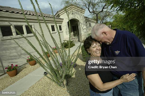 Jeff and Stella Pickford, standing in the front yard, will give up their house in Glendale, Ariz. For smaller quarters near LA to be near their...