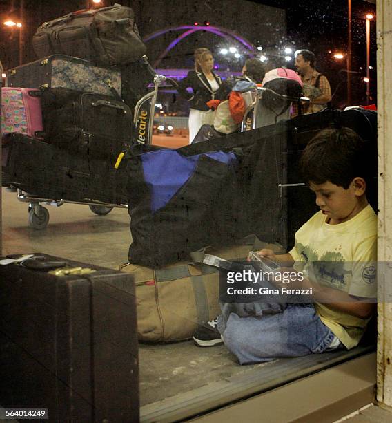 Eduardo Obregon sits amonst piles of luggage outside Terminal 1 near his family after his flight to North Carolina was cancelled at LAX after a power...